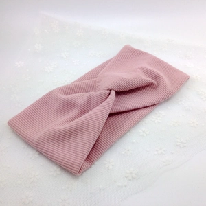 Detail of light pink ribbed knit headband featuring a classic twisted cross design