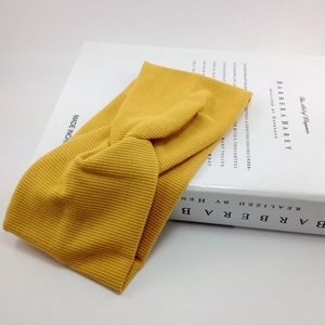 Detailed view of the yellow ribbed knit headband with a twist knot on white props
