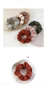 Detailed view of striped velvet scrunchies in various Morandi colors on a ceramic plate