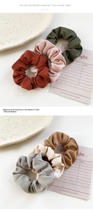 Detail of ribbed velvet hair scrunchies in Morandi colors on a white ceramic plate