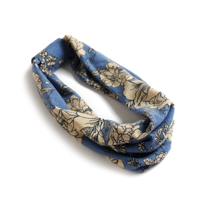 Détail d'un bandeau en coton bleu avec motifs floraux beiges et design torsadé élégant
