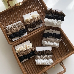 Set di tre elastici per capelli in raso nei toni della terra su schede in un cesto vintage