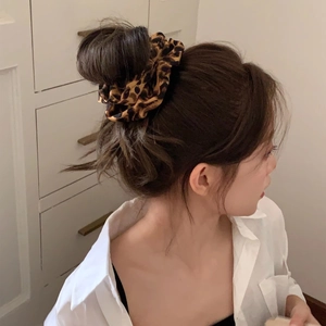 Chouchou élégant avec imprimé léopard porté sur un chignon par une femme mannequin