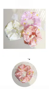 Close-up of three iridescent organza scrunchies with daisy prints and silk texture