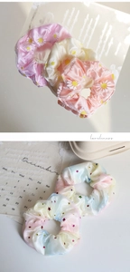 Detailed view of sheer organza scrunchies with daisy prints and star sequins