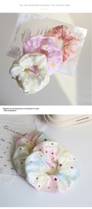 Detailed close-up of organza scrunchies with daisy prints and star sequins textures