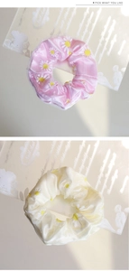 Detail showing pink and cream organza scrunchies with white daisy patterns and satin core