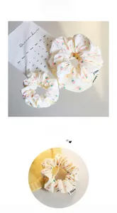 Detail von zwei Scrunchies mit Erdbeermuster aus cremefarbenem Stoff mit rotem Fruchtmuster