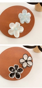 Detail of five-petal flower hair claw clips in cream jelly and black-white contrast colors