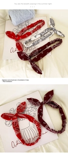 Detailed view of elastic paisley bunny ear headbands in red, white and burgundy colors