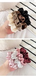 Gros plan de chouchous en satin crème et bordeaux posés sur une couverture en tricot