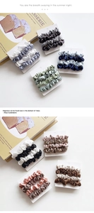Detail view of satin scrunchies in Morandi colors displayed on white cards over a book