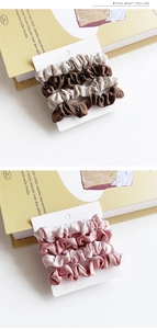 Detail of satin scrunchie set in earth tones and pink displayed on branded card packaging