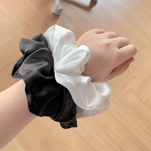 Set de coleteros de satén perlado blanco y negro en la muñeca de la modelo