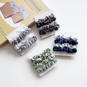 Minimalist satin silk scrunchies set in four gradient shades on a white brand card