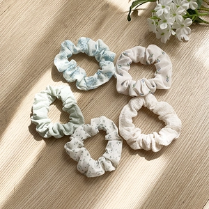 Lot de 5 chouchous floraux aux tons pastels présentés sur fond bois clair