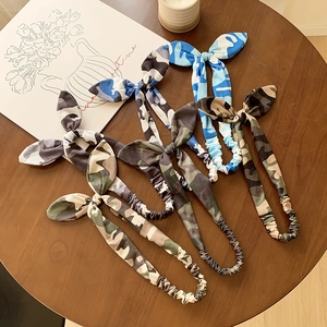 Lot de quatre bandeaux oreilles de lapin camouflage et tie-dye sur table en bois