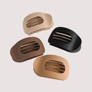 Dettaglio di quattro mollette ovali opache nei colori nero, marrone, beige e crema