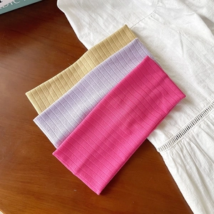 Bandeaux en tricot rayés en jaune, violet et rose sur un bureau en bois de style minimaliste