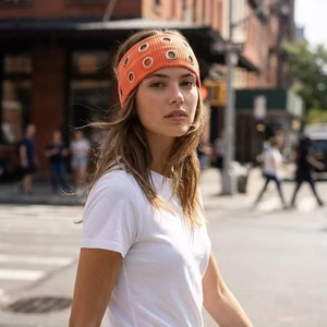 Elastic orange ribbed headband with silver metal eyelets for a punk rock style look