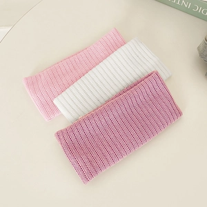 Trio of elastic knitted headbands in pink white and lilac on a clean cream background