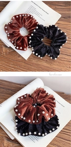 Detail of velvet pearl hair scrunchies in caramel and black on a vintage book