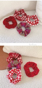 Detail of red tweed and houndstooth scrunchies on soft white textured fabric
