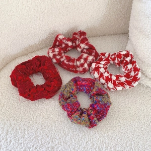 Set of four festive red plush scrunchies in solid and plaid styles on white texture