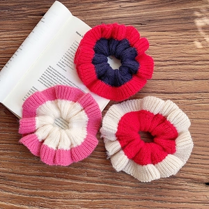 Three assorted knitted colorblock scrunchies on a wooden table with an open book