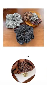 Détail de chouchous à motif cachemire avec un pendentif doré H sur le tissu
