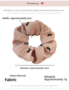 Detail view of light brown scrunchie with black butterfly embroidery showing 12cm diameter
