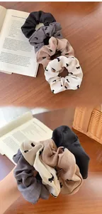 Close-up of hair scrunchies with velvet bow prints in black, grey, khaki and beige