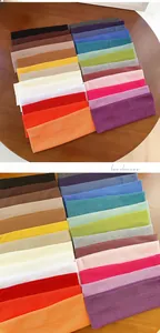 Detail showing various colors of elastic ribbed knitted headbands on a wooden table