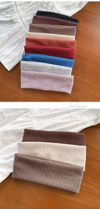 Detail of ribbed knit texture on assorted colorful elastic headbands on a wooden surface