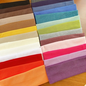 Elastic knitted ribbed headbands in a wide variety of solid colors on wooden background
