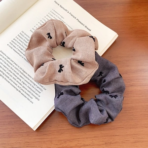 Chic scrunchie set with black bow patterns in khaki and charcoal grey on a vintage book