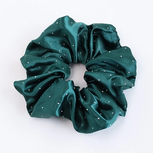 Gros plan sur chouchou en soie vert foncé avec détails en strass argentés et texture lisse