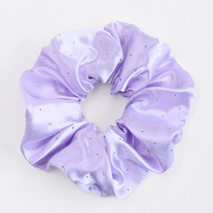 Détail du chouchou en satin lavande avec strass scintillants et texture en soie élégante