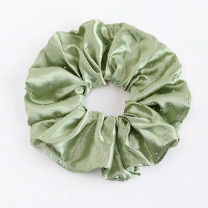 Détail macro du chouchou en satin vert clair avec des accents de strass argentés brillants