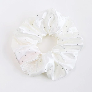 Détail d'un chouchou en satin blanc avec strass étincelants et texture soyeuse
