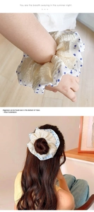 Detailed view of lace and blue polka dot scrunchie worn on wrist and in a hair bun