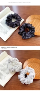 Detail von Polka-Dot-Netz-Haargummis in Schwarz und Weiß auf Vintage-Holzoberfläche
