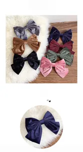 Detail showing various colors of velvet bow hair clips on a soft plush and wooden background