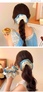 Detailed view of layered lace scrunchie with blue patterns on a ponytail and in hand