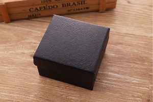 Primer plano de un joyero negro con textura de cuero sobre fondo de madera
