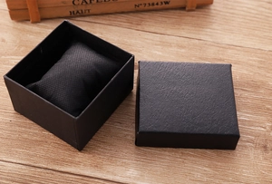 Vista macro de una caja cuadrada negra para joyas y relojes con cojín y textura de litchi