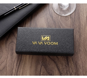 Primer plano de caja de regalo negra para reloj con logo dorado sobre madera