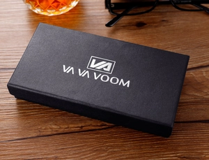 Detalle de la caja de regalo negra rectangular con logotipo plateado en relieve