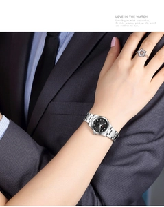 Detail of silver stainless steel watch with black dial and star ring on wrist