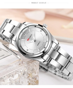 Detailed side view of silver stainless steel ladies watch on a soft pink background